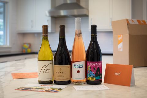 four bottles of wine on a countertop with a cardboard box and a card that says revel