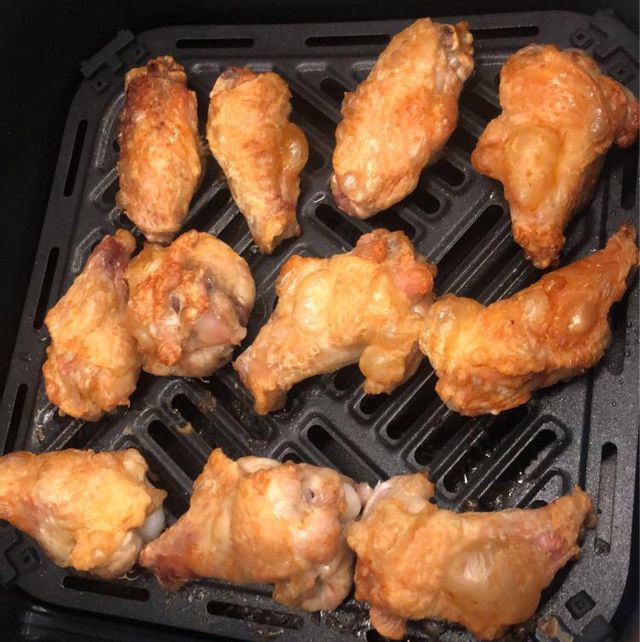 browned and crispy looking chicken wings in an air fryer basket