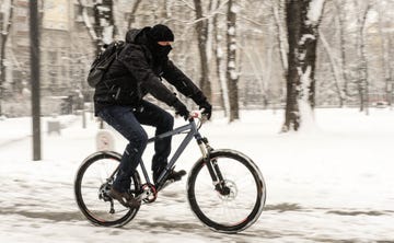 man in black clothing riding bicycle in the snow