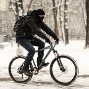 man in black clothing riding bicycle in the snow