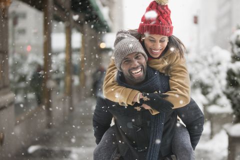 man carrying girlfriend piggyback in snow