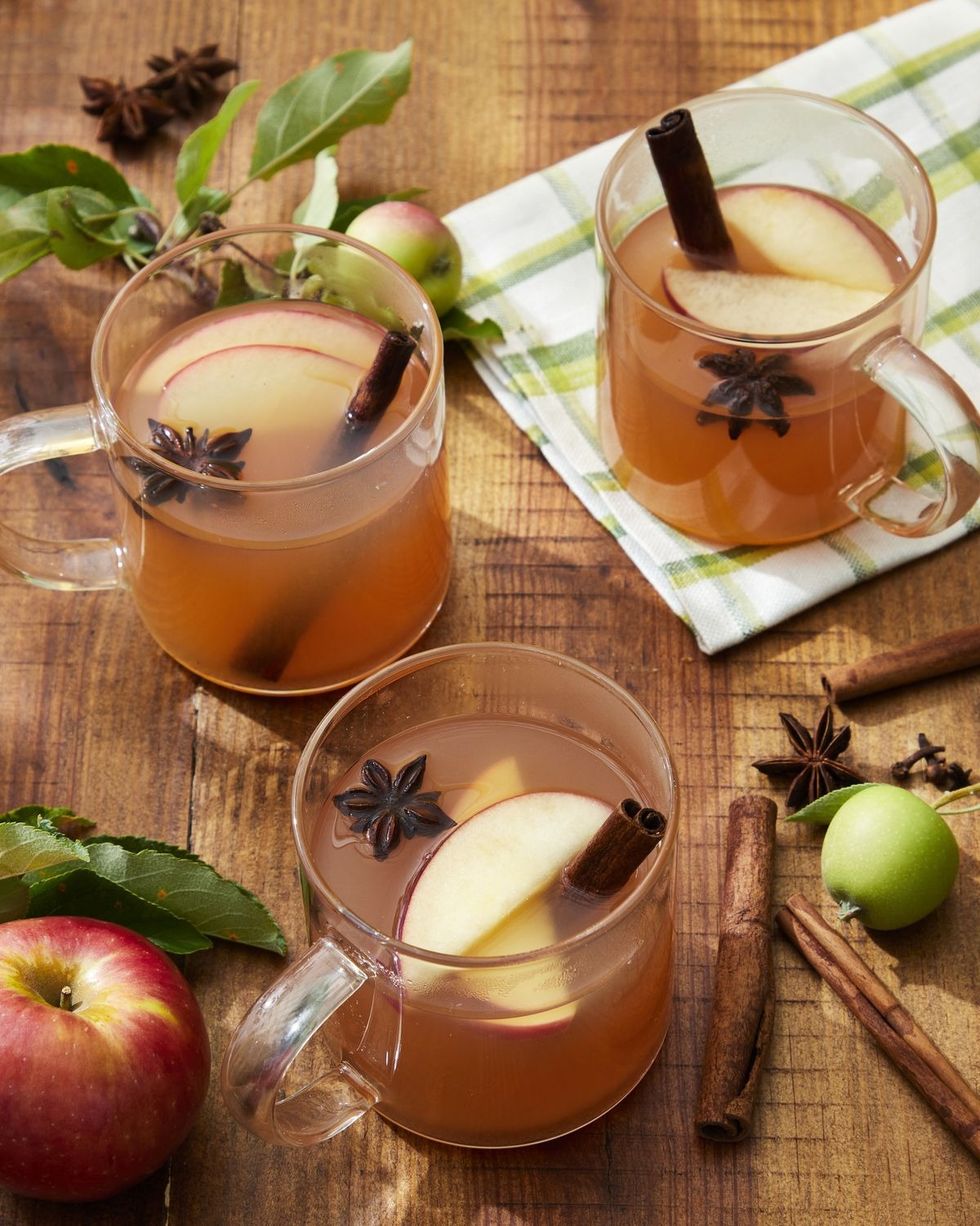 woodchuck warmer apple cider cocktail in glass mugs with slices of fresh apple a cinnamon stick and star anise