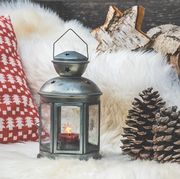 cozy sitting area on wooden veranda with lambskin, lantern and red and white pillows with christmas pattern