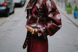 a person holding a stylish handbag while dressed in a maroon outfit