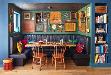 a dining nook with a navy leather banquette and collection of camp themed finds hanging above