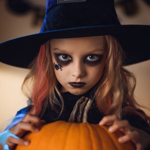 portrait of little witch halloween with a spider painted on her face