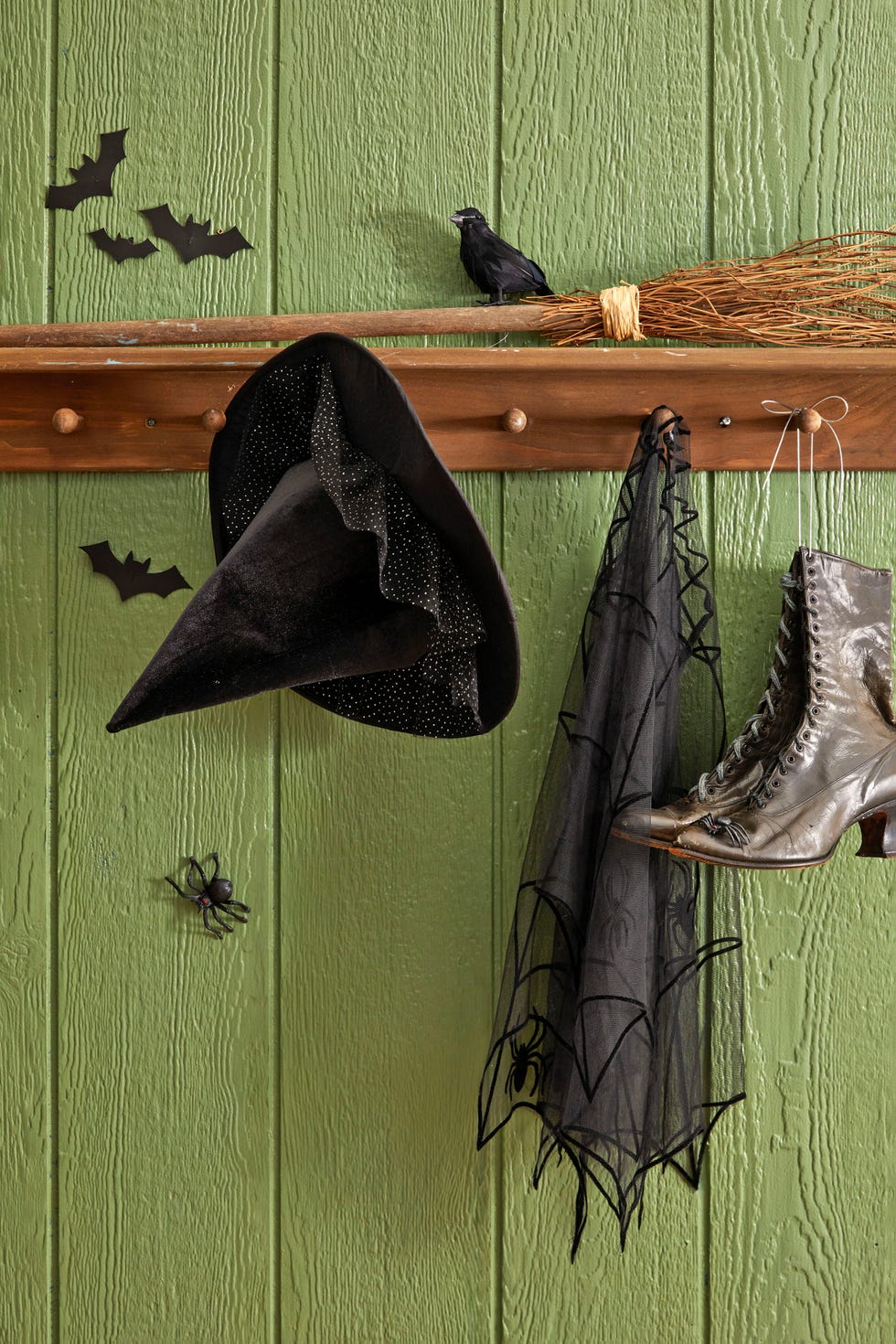 a witch hat cape boots and broom set up on a shelf inside the front door to act as a witches station