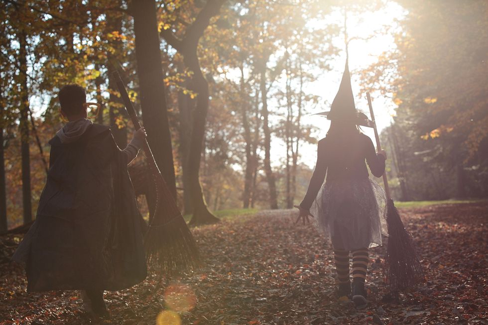 siblings dressed up as witch and wizard for halloween, walking in the woods