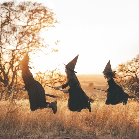 three kids dressed as witches on broomsticks