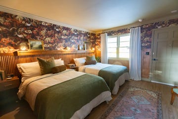 bedroom with two double beds, dark floral wallpaper, tambour paneling behind bed