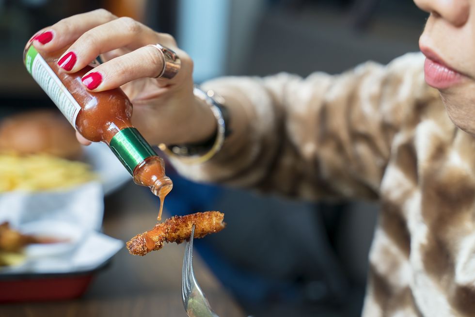 woman adding hot sauces on crispy, crunchy fried chicken fast food