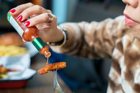 woman adding hot sauces on crispy, crunchy fried chicken fast food