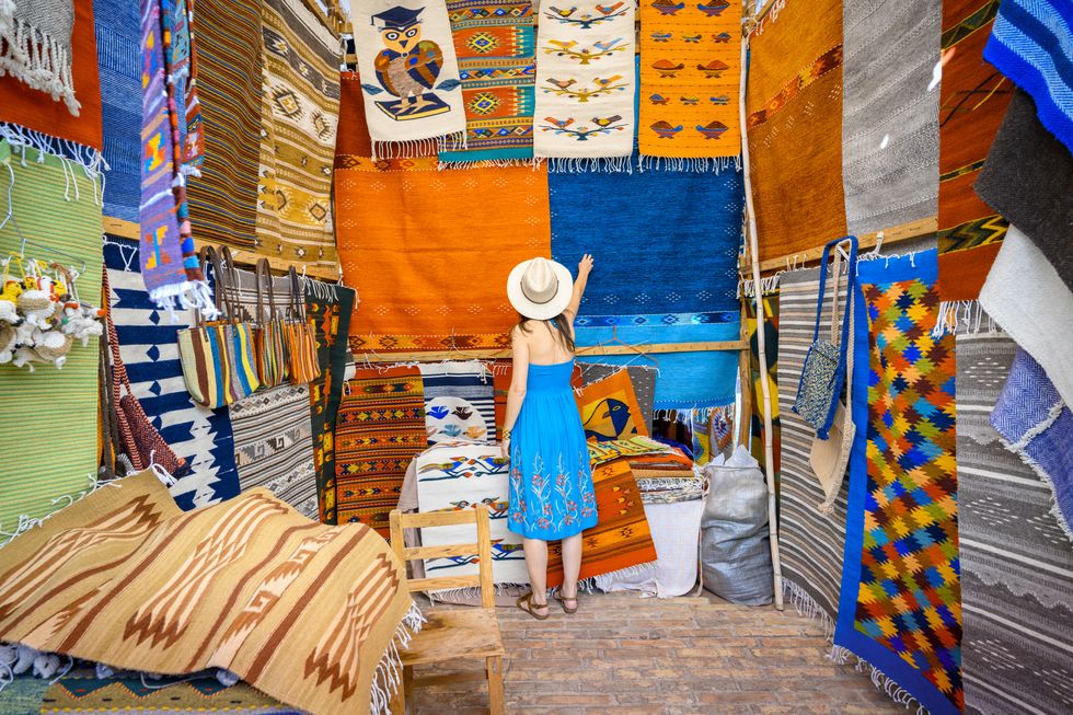 woman admiring the handmade rugs in oaxaca valley, mexico