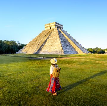 een vrouw staat voor de piramide van kukulcán in chichén itzá