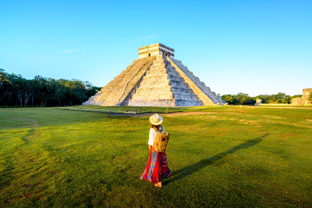 een vrouw staat voor de piramide van kukulcán in chichén itzá
