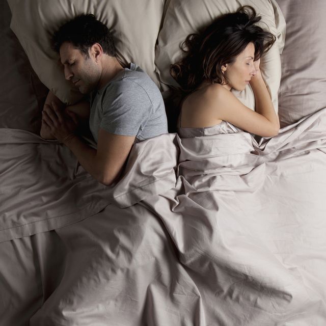 woman and a man lying back to back in  bed