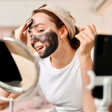woman applying black charcoal facial cleansing mask