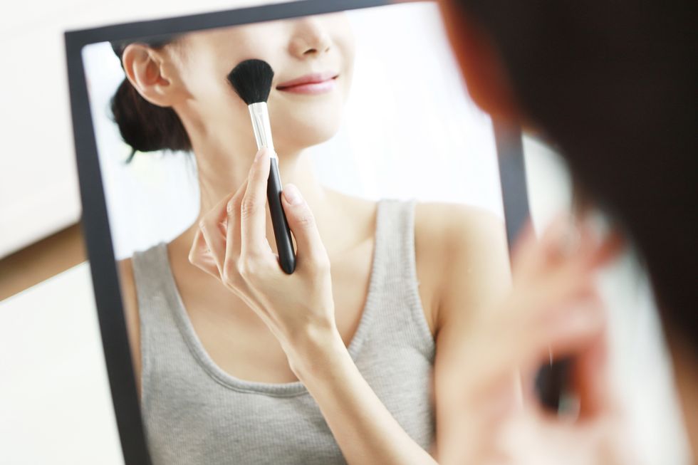 Woman applying blush in mirror