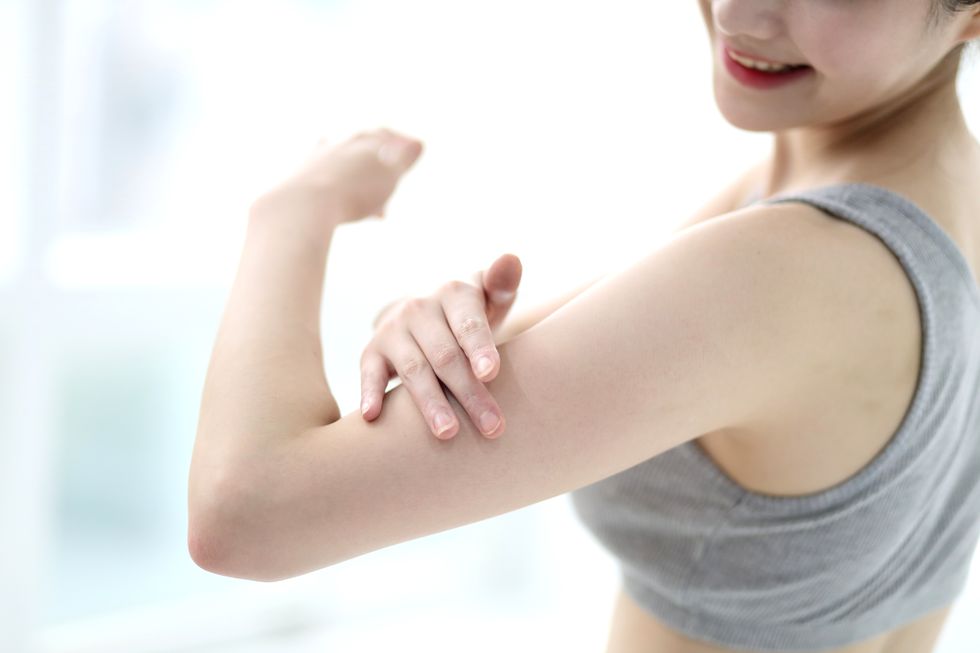 Woman applying body lotion on arm