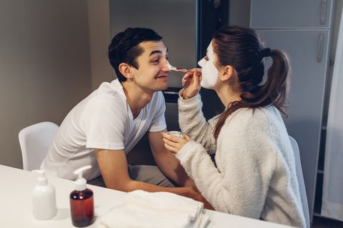 woman applying clay mask on her boyfriend's face