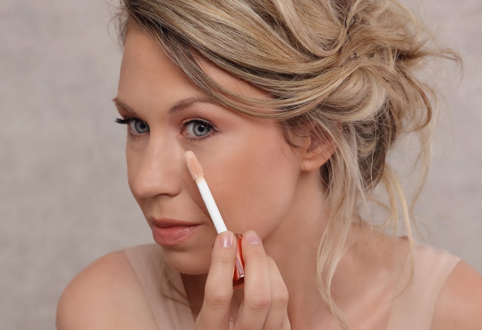 woman applying concealer to cover dark circles under eyes