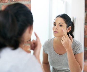 woman applying a dot of cream on her face