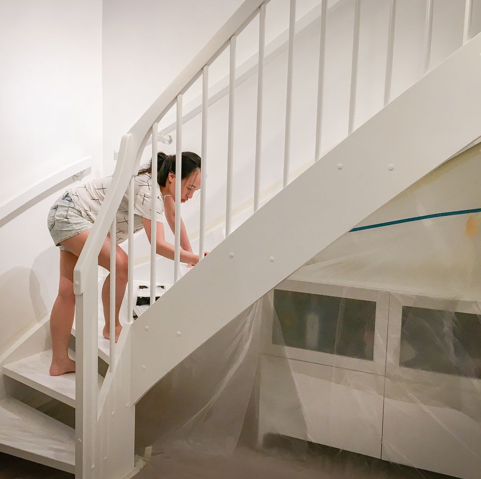 woman applying fresh white paint to the stairs