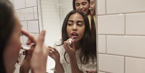 Woman applying lipstick while reflecting in mirror