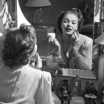 woman applying make up in front of mirror