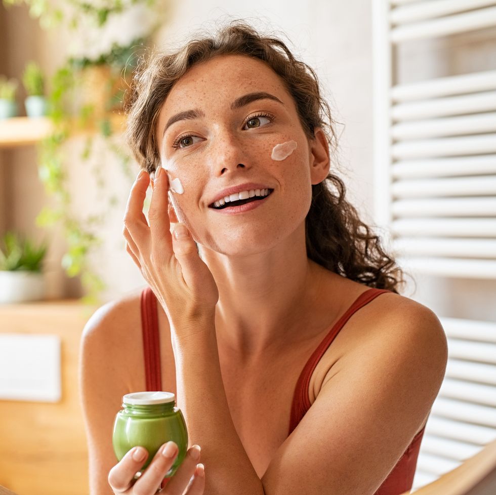 woman applying moisturiser on face during morning routine