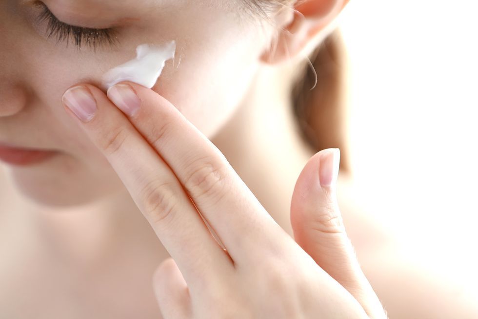Woman applying moisturizer on face