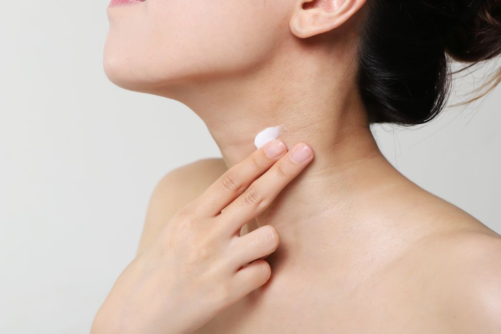 woman applying moisturizer on neck