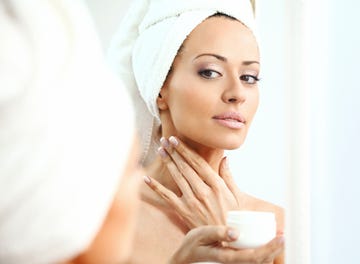 woman applying moisturizer onto her neck