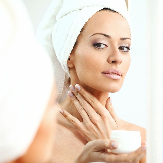 Woman applying moisturizer onto her neck
