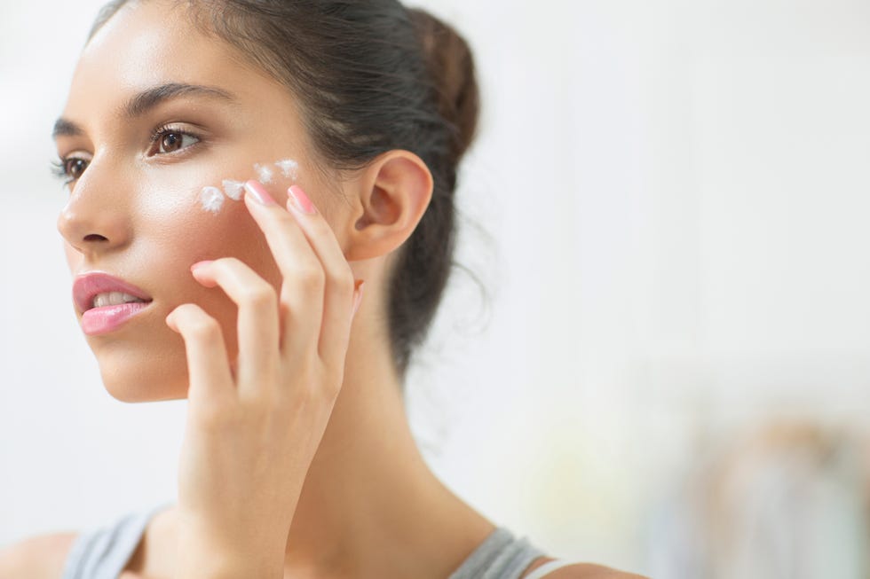 Woman applying moisturizer to cheek