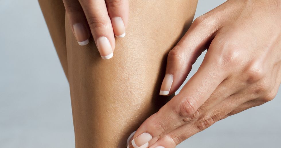 woman applying moisturizer to legs, cropped