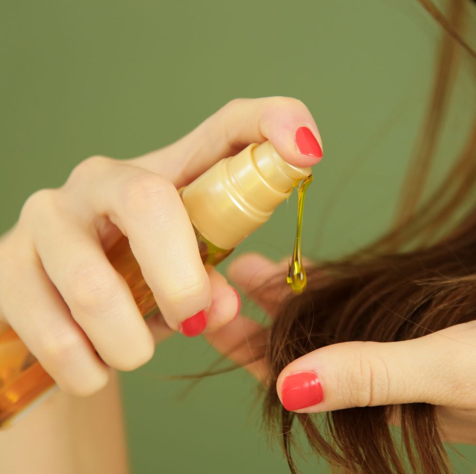 woman applying oil on hair ends, split hair tips, dry hair or sun protection concept