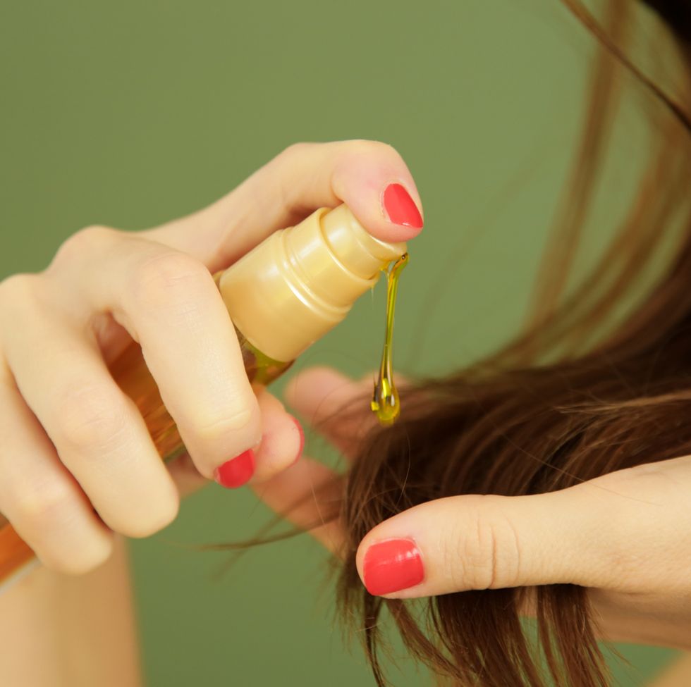 woman applying oil on hair ends, split hair tips, dry hair or sun protection concept