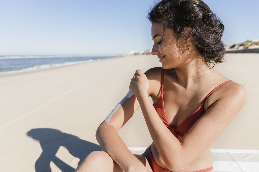 woman applying sunscreen at beach on sunny day