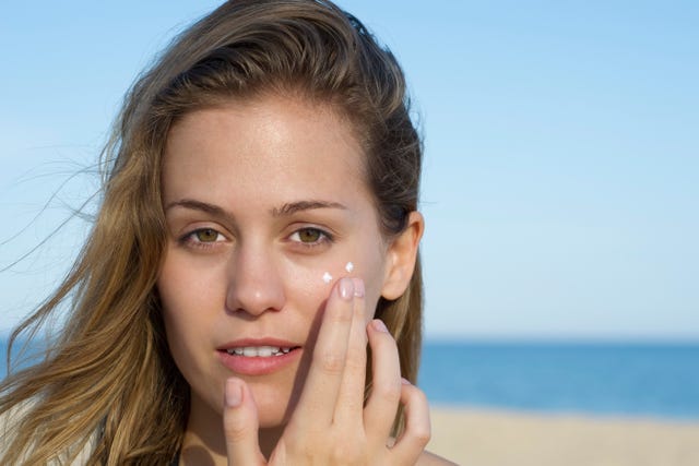 mujer se aplica crema en la cara al aire libre