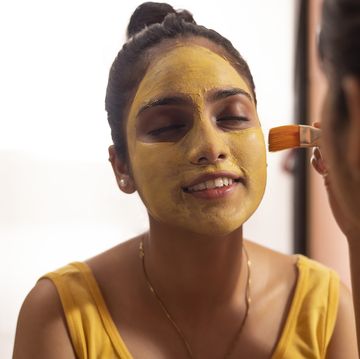 woman applying turmeric face pack on her friend's face