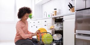 a woman loading a dishwasher in the kitchen