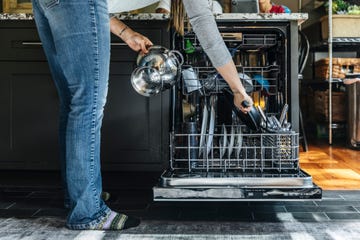 woman arranging utensils in dishwasher at home
