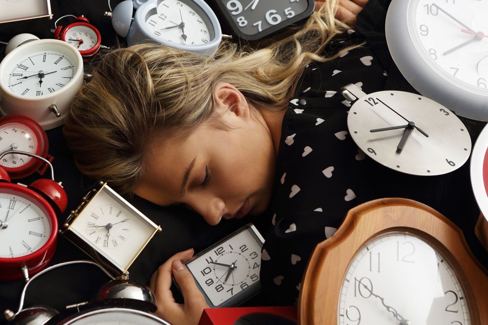 woman asleep surrounded by clocks