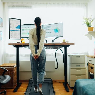 woman at home office is walking on under desk treadmill