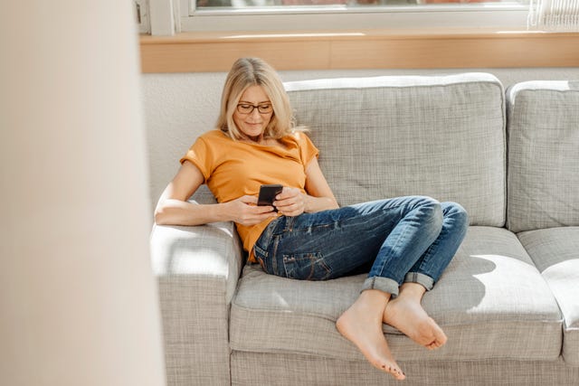 Woman at home on couch using cell phone