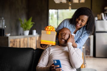 woman at home surprising her husband with a gift