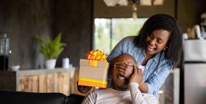 woman at home surprising her husband with a gift