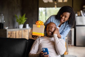 woman at home surprising her husband with a gift