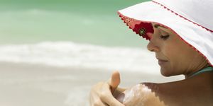woman at the beach applying sunscreen